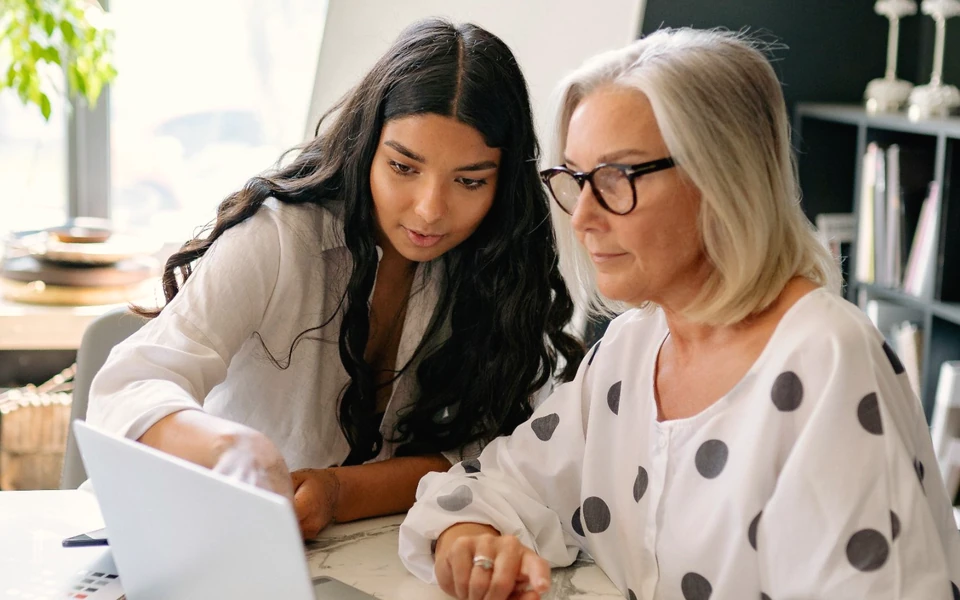 An educator talking with a longtime employee at her desk
